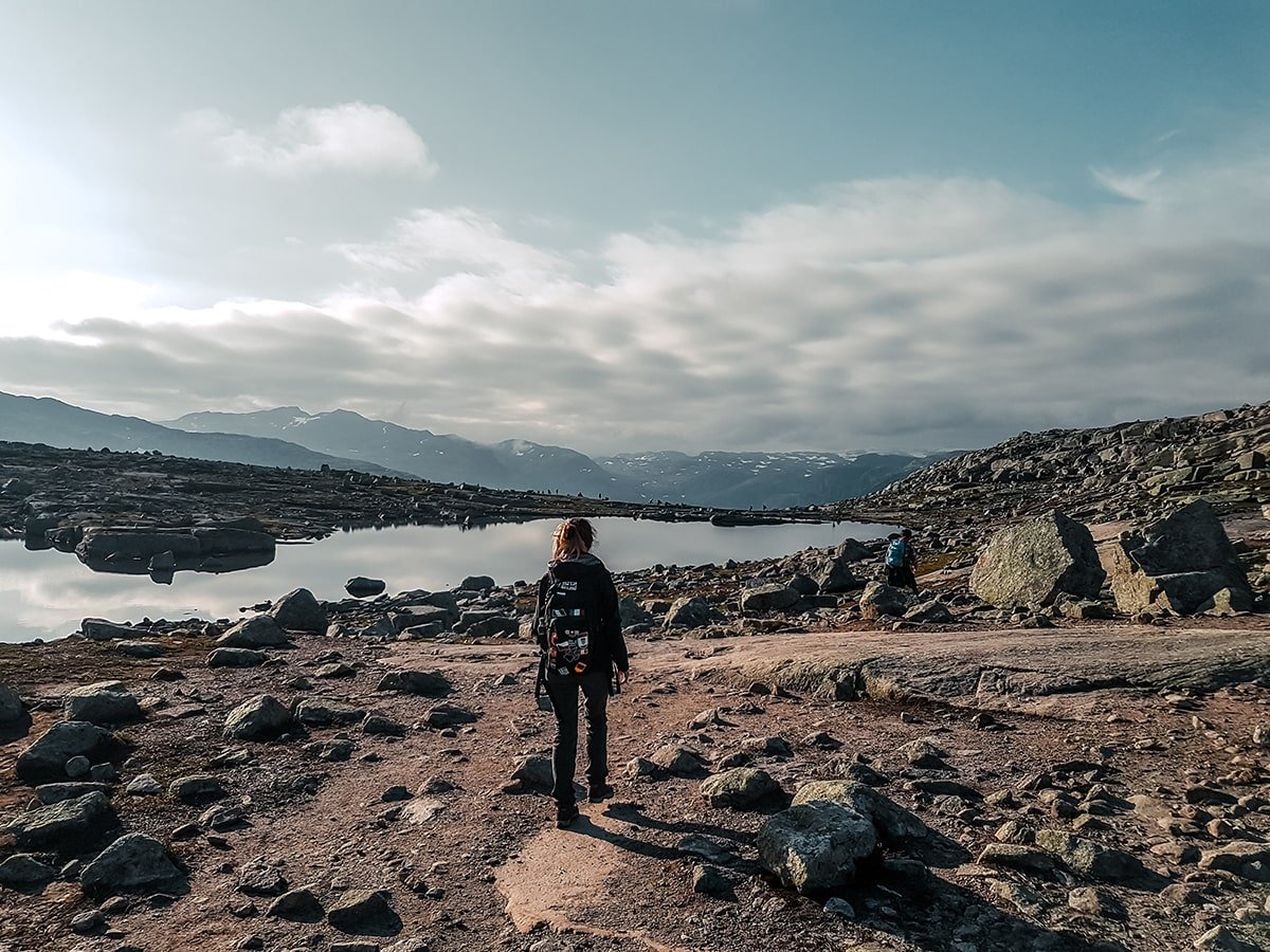 Hiking Trolltunga on a rocky terrain with a lake