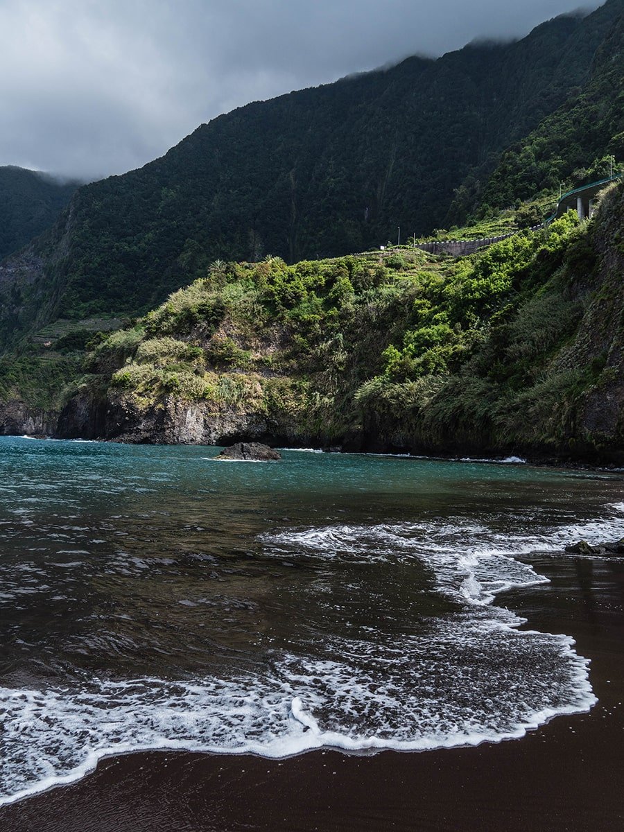 Black sand beach in Madeira with cliffs in the background