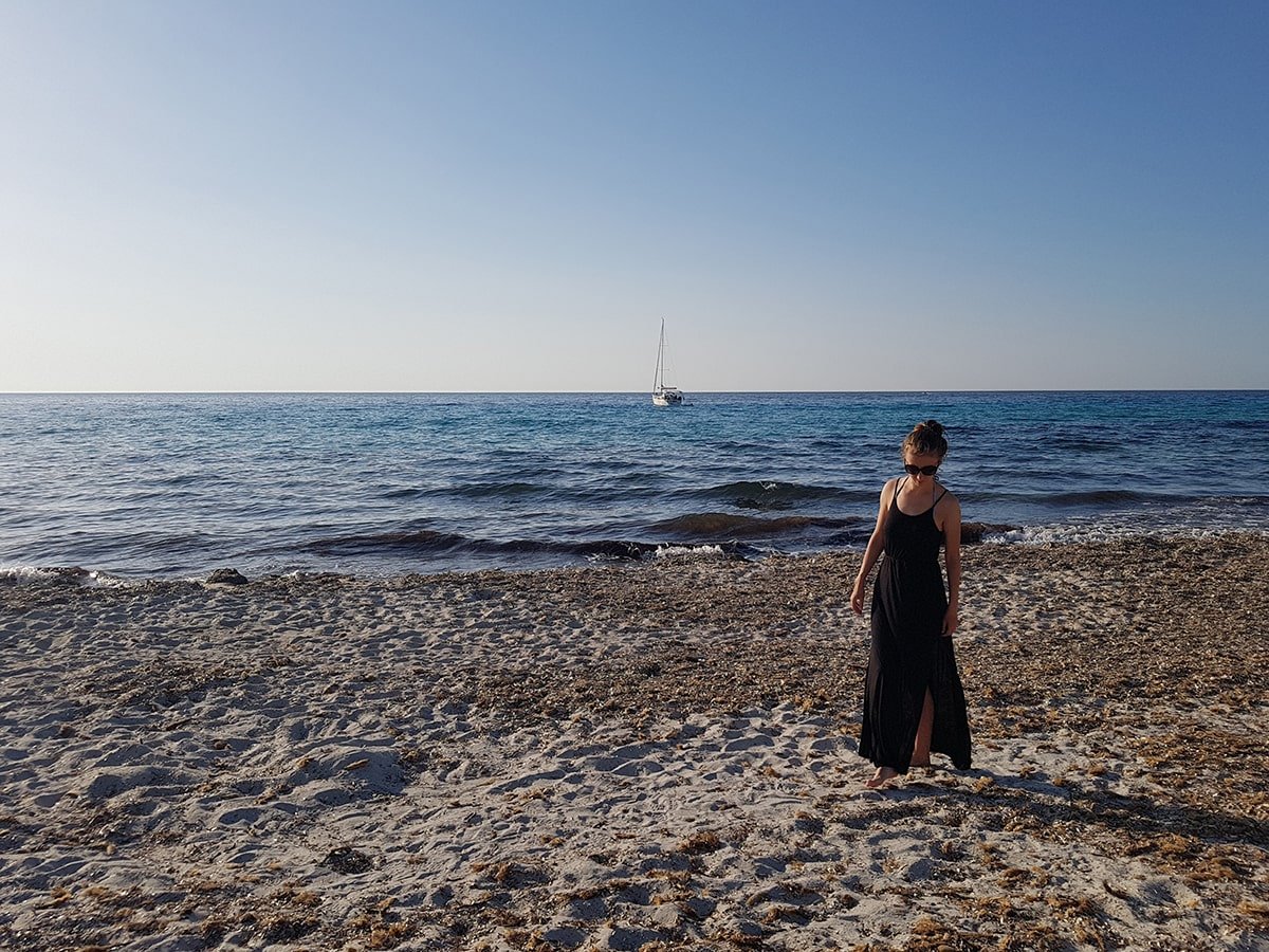 A woman in black dress walking on the beach in Corsica