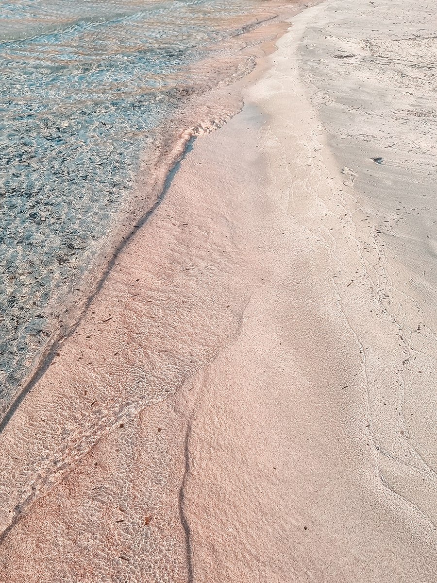 Fine pink sand and transparent water