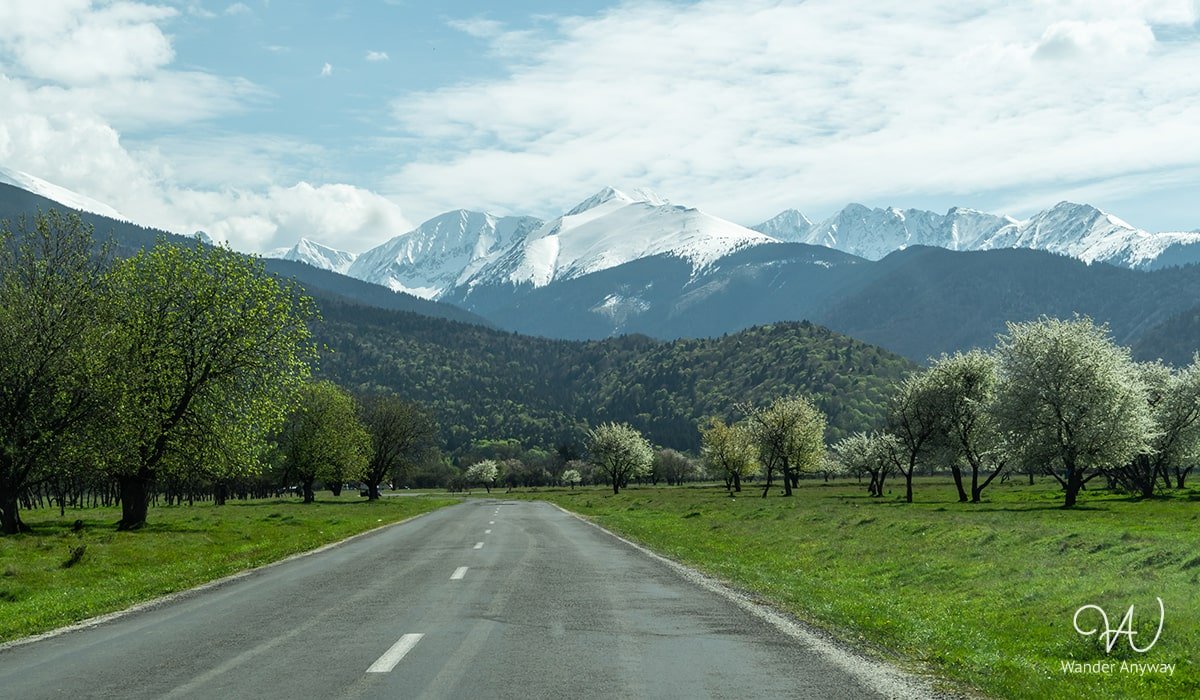 Road view with snowy peaks in Transylvania towards the Sâmbetei Valley