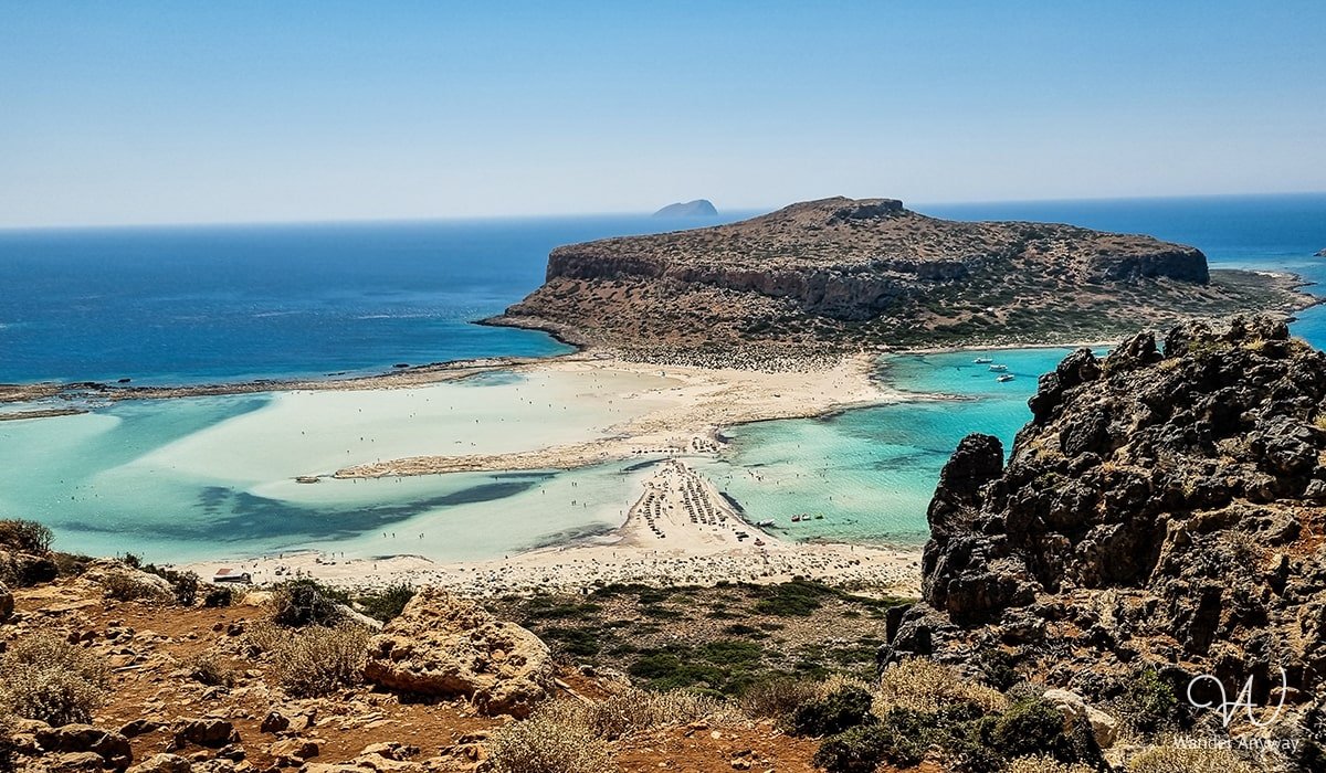 View of Balos Beach, Crete, with turquoise waters and white sandy beaches surrounded by rocky cliffs.