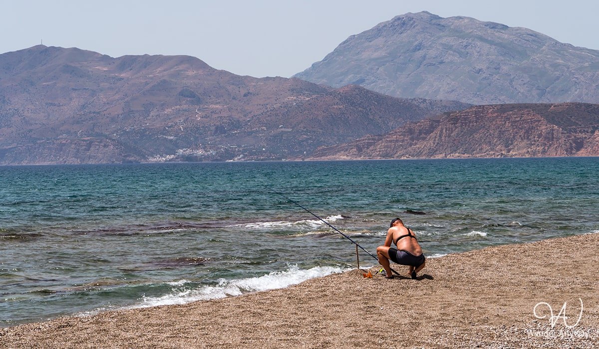 Visitors at Afrathias Beach, enjoying the black sand and clear shallow waters in a quiet setting. (Beaches to Discover in Rethymno and Heraklion)
