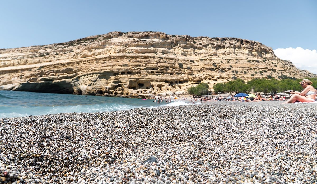 Matala Beach with ancient caves carved into the cliffs, popular for its history and hippie culture.