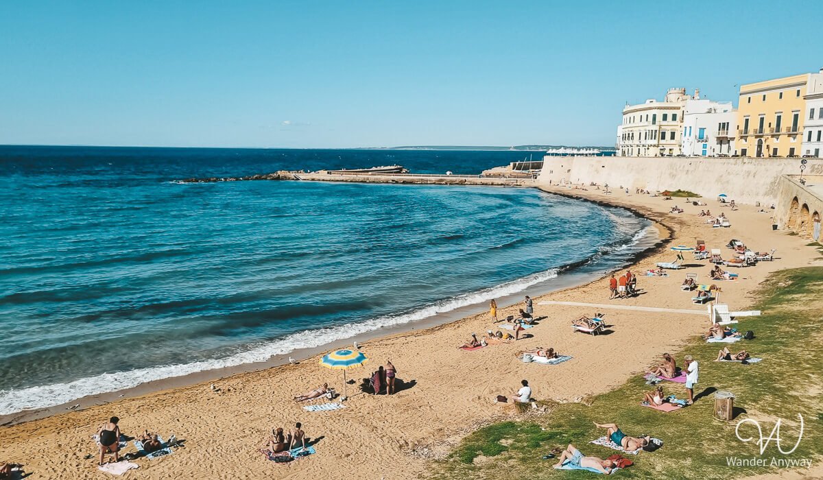 Spiaggia della Purità, a golden sandy beach in Gallipoli’s old town, offering crystal-clear waters for a perfect seaside escape on a day trip from Lecce by train.