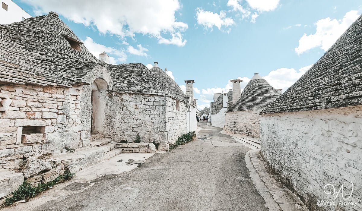 Peaceful cobblestone street lined with historic trulli homes in Alberobello, Puglia.