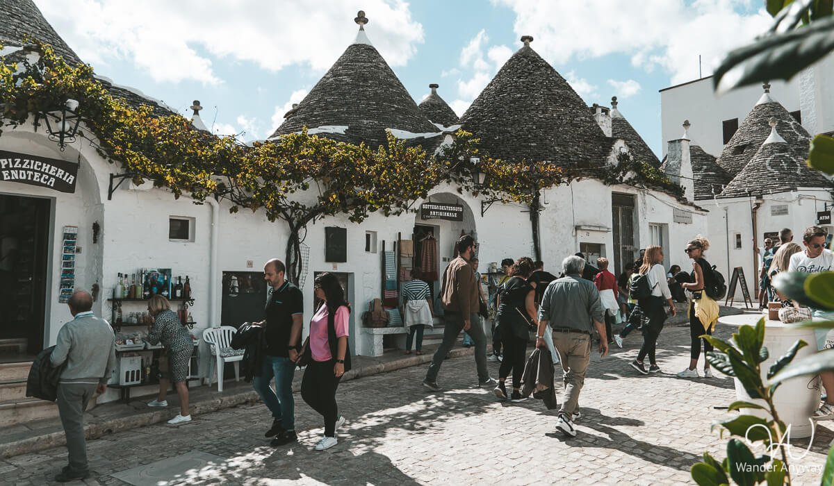 Tourists exploring a charming trulli-lined street, is Alberobello worth visiting?