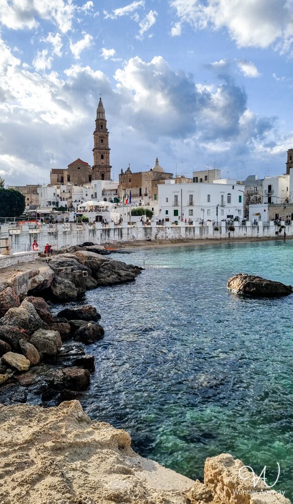 View of the Monopoli coastline with sandy coves and historic buildings by the sea.