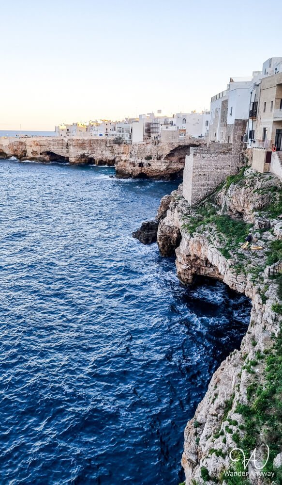 Cliffside view of Polignano a Mare with white houses perched above the sea.